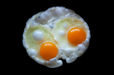 Two fried eggs Isolated on a black background view from above