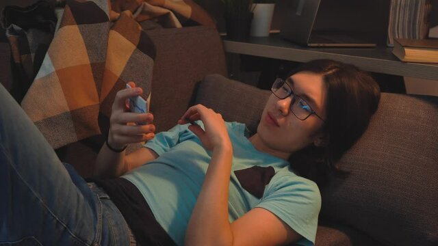 Asian Handsome  Guy is  Laying on the Sofa Writing an Ideas on Stickers 