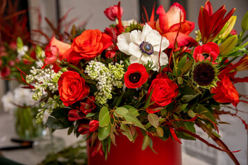Flower arrangement in red shades of orchids, roses, sunflowers, lilies, alstroemerias and ornithogalums in a red box. Professional florist work