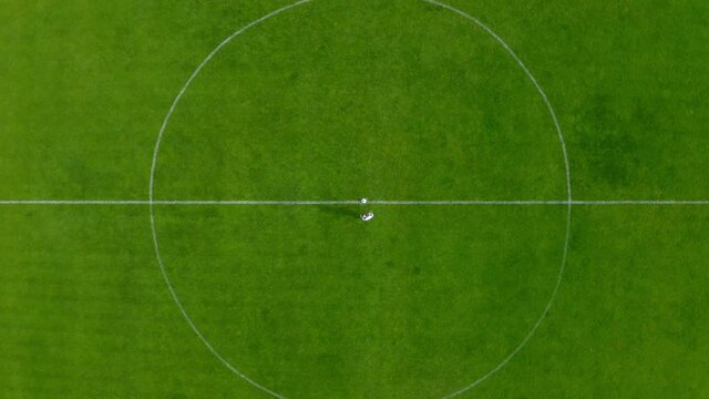 Drone footage of a professional football soccer player at the center point of a football stadium, the shot is moving to the center. 4k