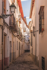 Fototapeta na wymiar Narrow cobblestone backstreet in old town (Albaicin or Arab Quarter) in Granada, Andalusia, Spain.
