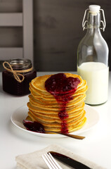 Stack of pancakes with cranberry jam and honey