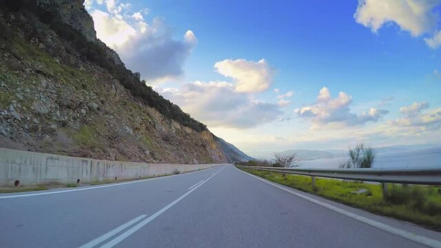 Beautiful nature POV drive, hilly scenery car travel, mediterranean coast asphalt road point of view, blue sky with clouds horizon