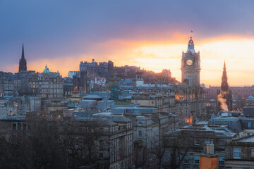 Fototapeta premium Classic sunset or sunrise cityscape view from Calton Hill taking in Princes Street, Edinburgh Castle and the Balmoral Clock Tower at Waverley Station in Edinburgh, Scotland.