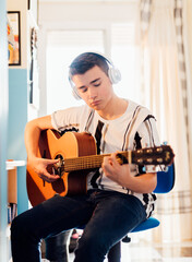 Teenage boy taking guitar lessons online. Technology concept.