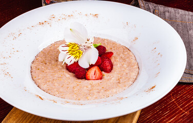Oatmeal porridge with strawberries and raspberries in a white plate. Healthy food