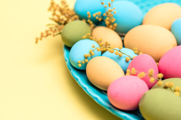Turquois dish with painted blue, green, yellow, and pink eggs with mimosa