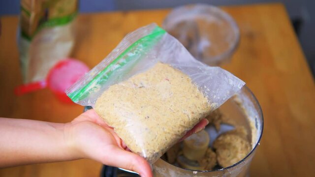 Hand forming homemade bird feeder suet of white organic flour, mealworms, raw peanuts and peanut butter, coconut oil from food processor in zipper reusable re-sealable plastic bag