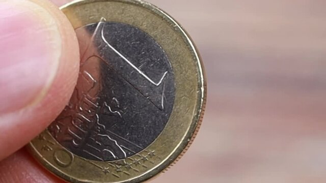 doigts tenant une pi&egrave;ve de 1 euro