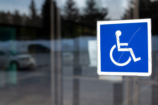 The International Symbol of Access icon, a blue square with a white graphic wheel chair and person, in a window in London Ontario Canada, February 2021.  