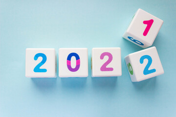 Cubes with colorful numbers on a blue background. Year change concept, from 2021 to 2022. Digit 2...