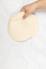 Empty Tortillas in the hand above white background with copy space