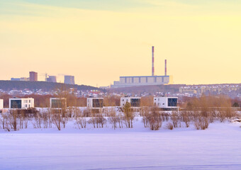 Obraz premium Winter morning on the Ob. New residential area on the frozen river bank in Novosibirsk, heat station pipes on the horizon