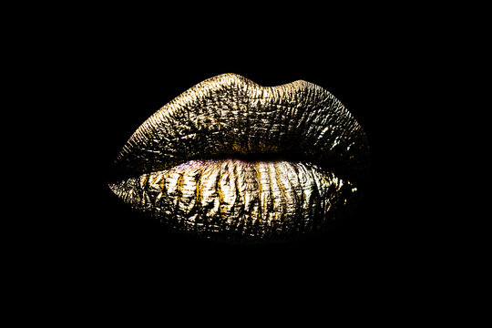 Closeup gold lips. Woman sexy golden lip makeup isolated on black background.