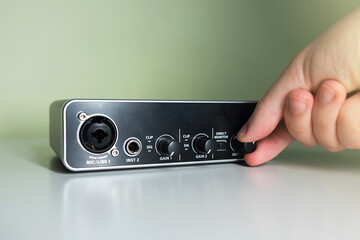 Hand plugin a turning a knob of an external USB Sound card. Home studio concept.