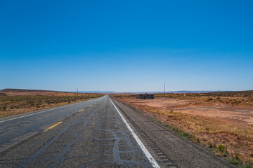 Panorama view of road running through the barren scenery of the American Southwest.