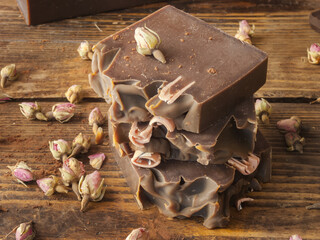 Bars of homemade chocolate soap and roses, on an old wooden background