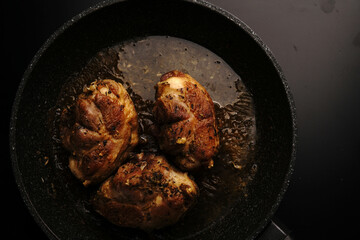 Large pieces of chicken fried in a frying pan. Top view.