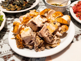 Close up view of fried chicken pieces in white plate surrounded by other food dishes on table