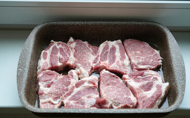 Raw pieces of pork laid in a bowl for further baking in the oven. In the kitchen.