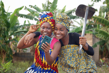 Two amazed African Nigerian female farmers joyfully staring at a smart phone 