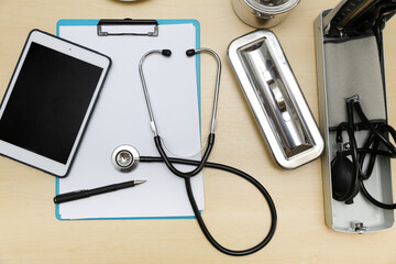 The doctor's desk had a note pad, a notebook, a pen, a stethoscope, a pressure gauge.