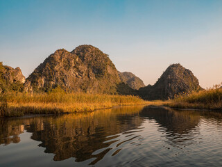 Asia, Vietnam, Van Long Nature Reserve. Scenic hills reflected on calm water.