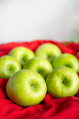 Green ripe apples on red fabric