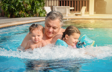 Portrait of grandfather and children in the pool.