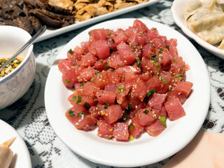 Japanese tuna sashimi in serving plate on table surrounded by other dishes