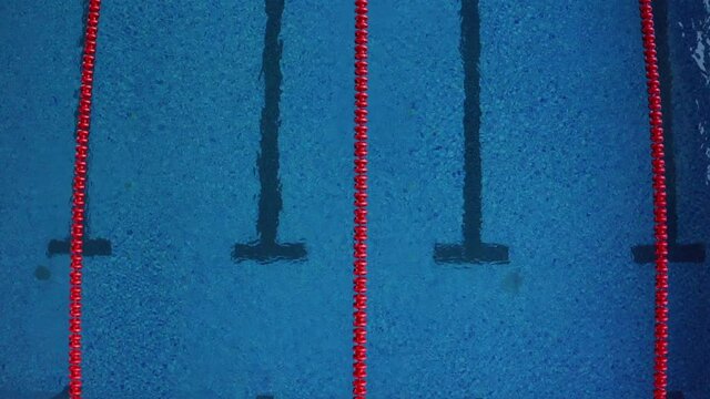 Flying slowly above the lanes of the swimming pool. Aerial view of transparent water