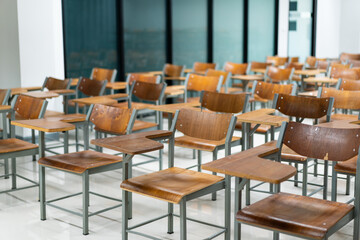 Wooden chairs are well arranged in the classroom. Empty classroom with vintage tone wooden chairs. Back to school concept..