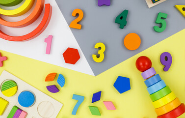 Wooden kids toys on colourful paper. Educational toys blocks, pyramid, pencils, numbers . Toys for kindergarten, preschool or daycare. Copy space for text. Top view