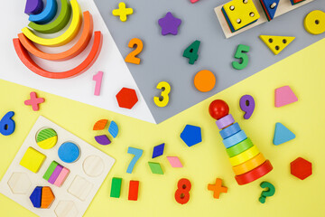 Wooden kids toys on colourful paper. Educational toys blocks, pyramid, pencils, numbers, train. Toys for kindergarten, preschool or daycare. Copy space for text. Top view
