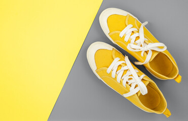 New pairs of yellow sneakers on gray yellow background with copy space. Lifestyle sneakers, sports shoes.