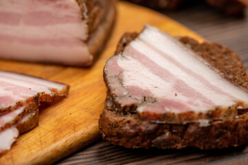 Sandwich with smoked brisket sliced on grain bread on a wooden cutting board.