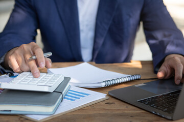 Close up businessman hand using calculator and working with  laptop calculate about finance accounting at coffeeshop outdor.finance accounting concept