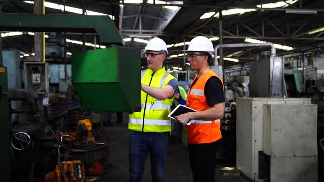 Workers wearing safety hat command computer to produce products by automate robot machines in factory workshop.