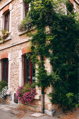 Facade of old stone buildings in Perouges, red windows, flowers, France