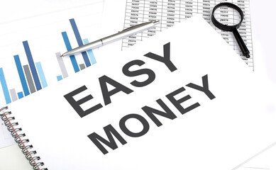 In the notebook, the text Easy Money , next to magnifier and a pen, the background is graphics.
