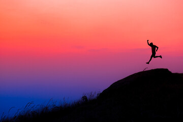Silhouette the man jump On the top of the hill 