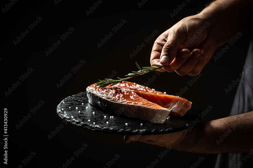 Wall mural chef marinating salmon fish, adds herbs, seasoning to fish, delicious gourmet seafood dish. banner, 