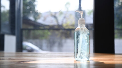 Bottle of alcohol hand sanitizer on wooden table with copy space for germ prevention or antibacterial hygiene.