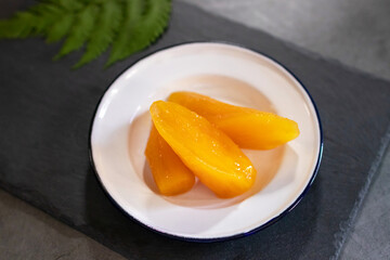 Sweet potato or Yam in syrup usually served coconut milk in vintage zinc coating dish on black stone background. Traditional desserts in Thailand.