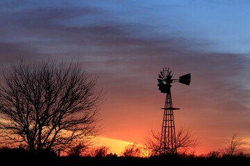 Fototapeta premium Kansas colorful Sunset with clouds and a Windmill silhouette out in the country north of Hutchinson Kansas USA.