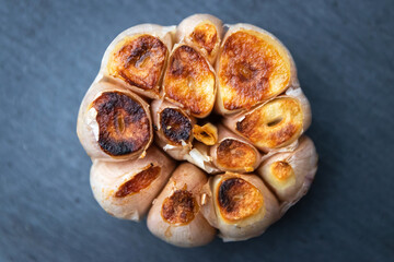 Garlic clove grilled on black stone background; top view.