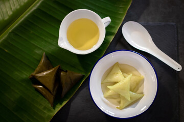 Dessert made with glutinous rice wrapped in banana leaves, triangle shape, boiled, eaten with syrup and ice. Thai Dessert; called Kao Tom Nam Woon. 