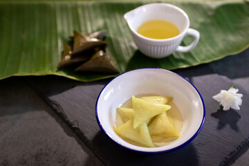 Dessert made with glutinous rice wrapped in banana leaves, triangle shape, boiled, eaten with syrup and ice. Thai Dessert; called Kao Tom Nam Woon. 