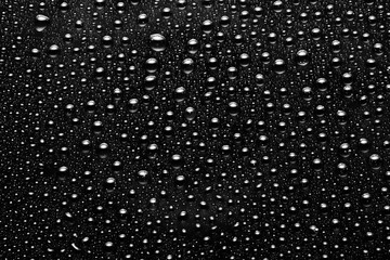 background of drops on a black glossy surface close up