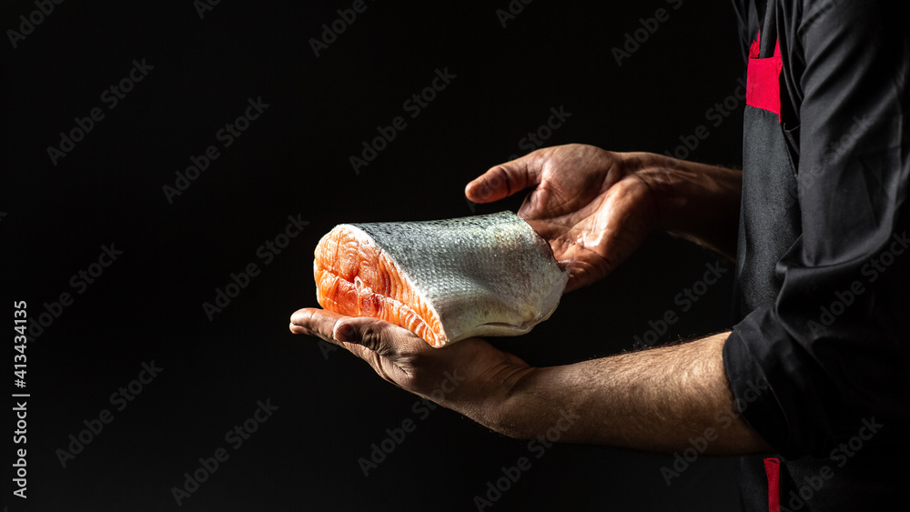 Wall mural cook hands prepares steak fish salmon, the big piece salmon is in the hands of the chef cook. banner